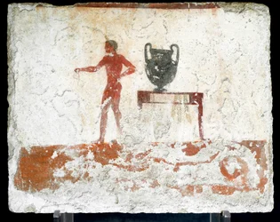 Etruskische kunst: een jonge naakte ephebe bij een tafel waar een vaas op staat. Fresco van het graf van de 
