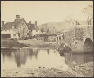 [Gezicht op een huis aan de overkant van een rivier met een brug naar rechts].