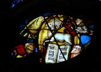 Het westelijke roosvenster met een scène uit het Boek Openbaring: lam met zeven horens en zeven ogen opent het boek. Let op de symbolen van de 4 evangelisten (5:7)