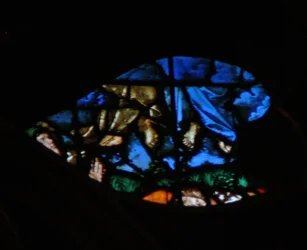 Het westelijke roosvenster met een scène uit het Boek Openbaring: opstanding van de getuigen en hun hemelvaart (in de blauwe wolken) terwijl de toeschouwers verbaasd zijn (11:11-13)