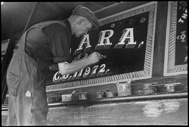 Frank Jones, aan het werk met het schilderen van het naampaneel op een binnenschip, 20e eeuw (foto)