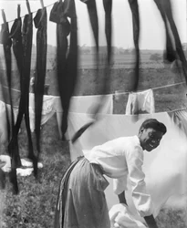 Een jonge Afro-Amerikaanse vrouw hangt wasgoed te drogen in Newport, Rhode Island, ca. 1902 (zw/w foto)