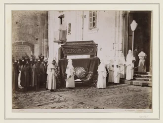 Begrafenisstoet van monniken met puntmutsen bij de ingang van een kerk in Italië
