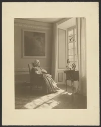 [Interieur met zittende vrouw in kostuum].