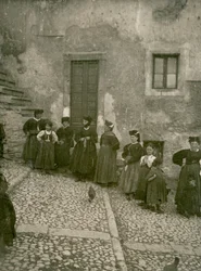 Vrouwen en kinderen in traditionele kleding op trappen naar huis, Abruzzo, Italië