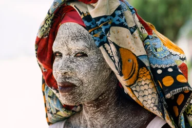 Een vrouw draagt gemalen schorscrème mussiro om haar gezicht te beschermen tegen de zon. Mozambique