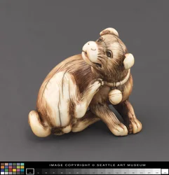 Netsuke gemodelleerd als een hond die zijn nek krabt