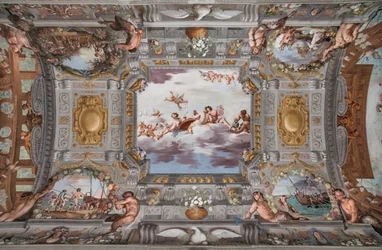 Huwelijksbanket. Op de wolken zitten Bacchus, Ariadne en Venus met een figuur die wijn inschenkt aan een ronde tafel. De andere goden kijken van een afstand toe.