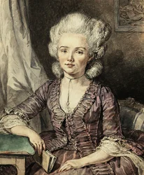 Een jonge dame zittend aan een tafel met een boek