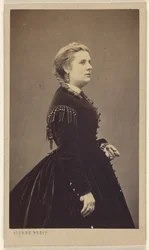 [Ongeïdentificeerde vrouw in donkere jurk, staand, in profiel].