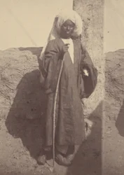 [Portret van een jonge Noord-Afrikaanse man die tegen een pilaar staat].