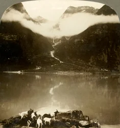 Grytereids gletsjer glinsterend boven drijvende wolken, over het rustige Lake Olden, Noorwegen, ca. 1905