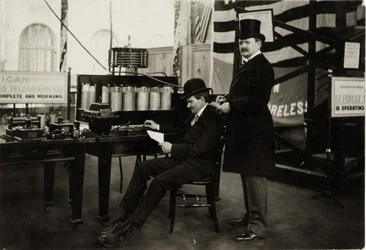 Lee DeForest (zittend) zendt een draadloos telefoongesprek in het Department of Electricity op de Wereldtentoonstelling van 1904