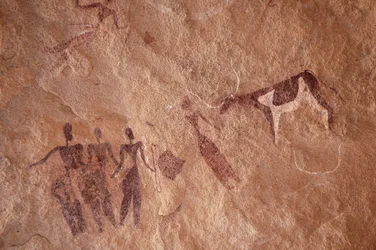 Rotstekeningen, Prehistorie: Rotsschildering van een groep personages en een tweekleurige koe met grote hoorns in een versierd onderkomen, in het Uweinat-massief, Egypte. (Periode van 8000 tot 3000 jaar v.Chr.). Fotografie