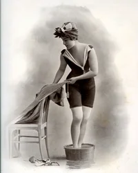 Jonge vrouw in badpak (uit de Belle Epoque) neemt een voetbad, rond 1900 (zwart-wit foto)