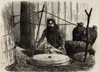 Turkmeense vrouw die de graanmolen gebruikt. Gravure ter illustratie van de reis naar Zuidelijk Afrika van 1840 tot 1856, in 