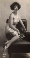 Een jonge vrouw poserend in haar onderjurk, zittend in een fauteuil