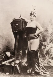 Portret van een gedeeltelijk naakte vrouw leunend op een antieke camera.