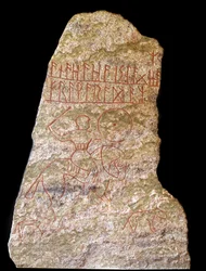Een stele met runeninscripties die een Vikingruiter met een hond voorstelt (steen)