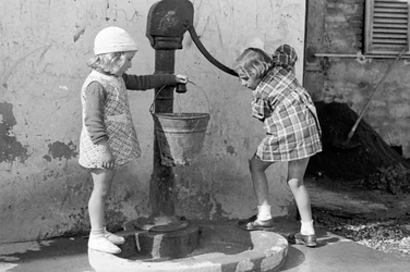 Kleine meisjes vullen een emmer water, 9 mei 1939 (z/w foto)