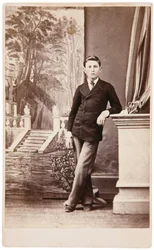 Studioportrait van jonge man voor geschilderde achtergrond van trap en tuin